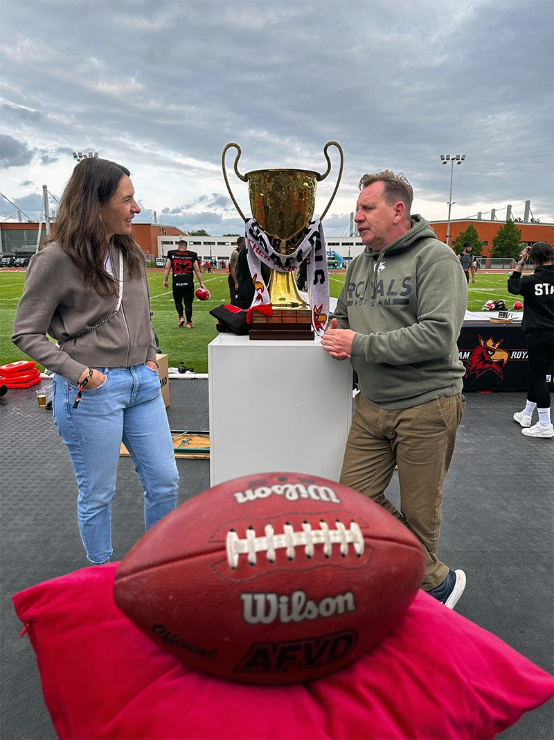 Dr. Szabadi beim Football-Event neben Siegerpokal und Football – Engagement der Praxis für Sport und gesunde Athletenzähne.